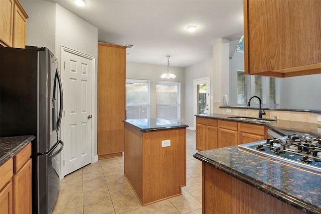 kitchen with a kitchen island, sink, dark stone counters, light tile patterned floors, and stainless steel refrigerator with ice dispenser