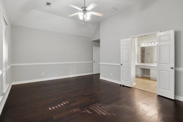 unfurnished bedroom featuring ensuite bath, built in desk, vaulted ceiling, dark hardwood / wood-style floors, and ceiling fan