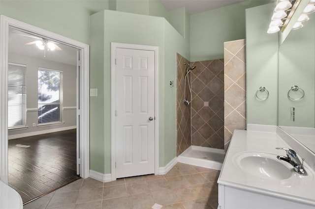 bathroom with tile patterned floors, ceiling fan with notable chandelier, vanity, and a tile shower