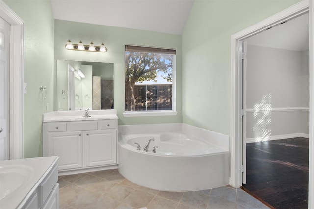 bathroom with vanity, vaulted ceiling, a bath, and tile patterned floors