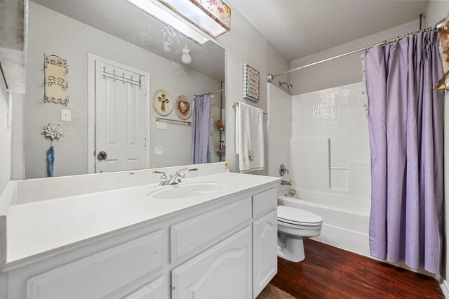 full bathroom featuring shower / bathtub combination with curtain, a skylight, vanity, wood-type flooring, and toilet