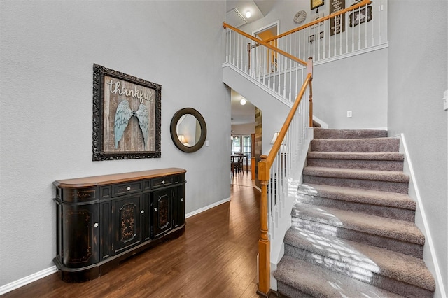 stairs with wood-type flooring and a towering ceiling