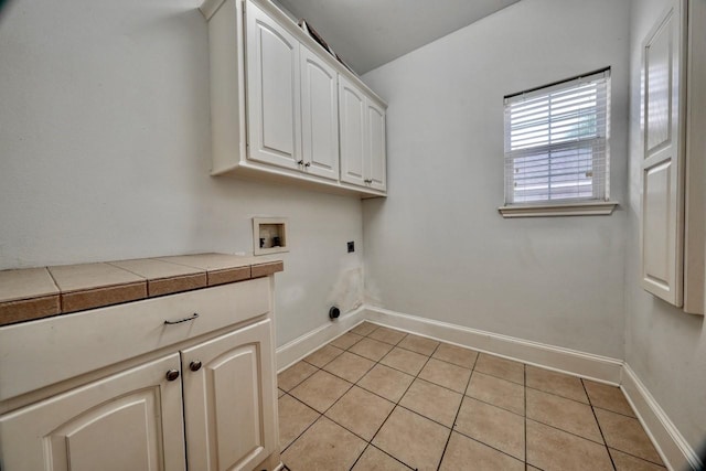 clothes washing area with washer hookup, light tile patterned floors, cabinets, and electric dryer hookup