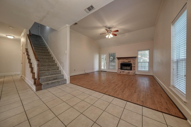 unfurnished living room with a fireplace, ornamental molding, ceiling fan, and light tile patterned flooring