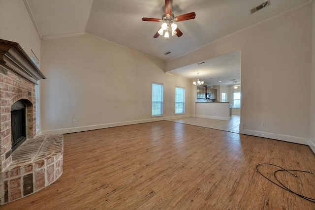 unfurnished living room with crown molding, a fireplace, ceiling fan with notable chandelier, and light wood-type flooring