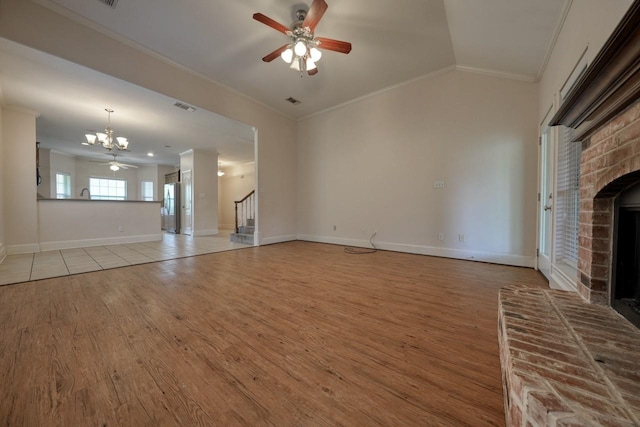 unfurnished living room with crown molding, ceiling fan with notable chandelier, a fireplace, and light hardwood / wood-style floors