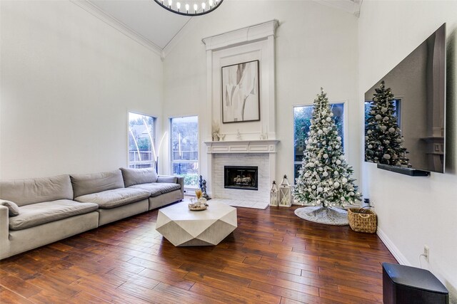 living room with crown molding, dark hardwood / wood-style floors, high vaulted ceiling, and a brick fireplace