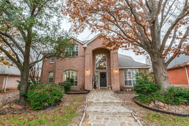 traditional home with a shingled roof and brick siding