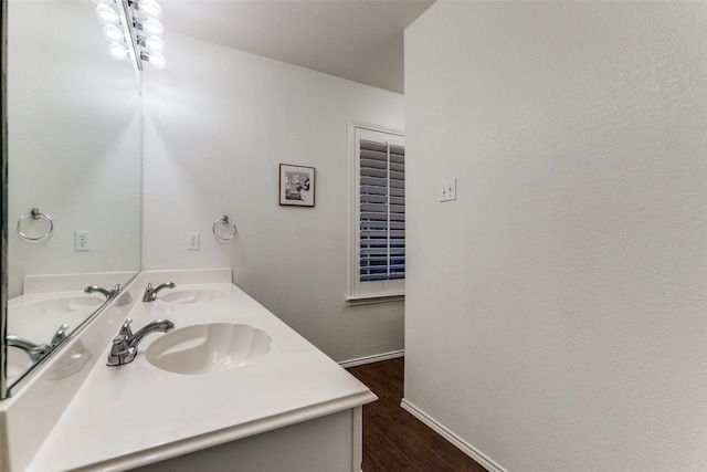 bathroom featuring double vanity, a sink, baseboards, and wood finished floors