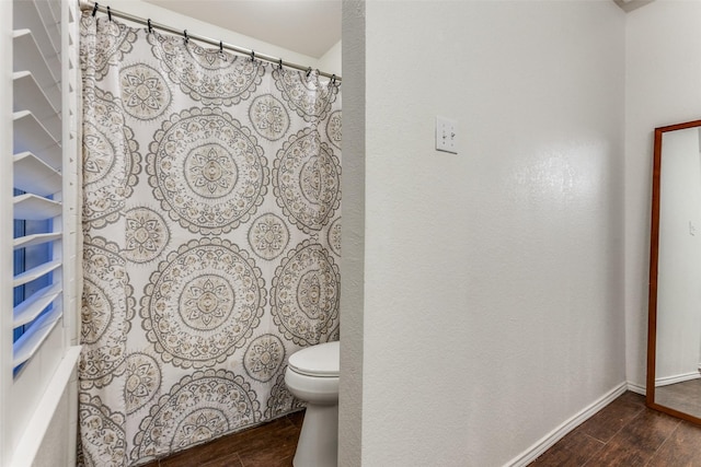 bathroom with toilet, baseboards, and wood finished floors