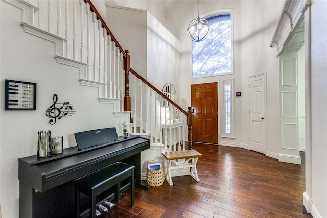 entryway featuring a healthy amount of sunlight, dark wood-type flooring, an inviting chandelier, and a towering ceiling