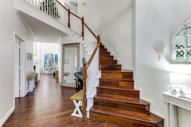 stairs featuring hardwood / wood-style flooring, a high ceiling, and baseboards