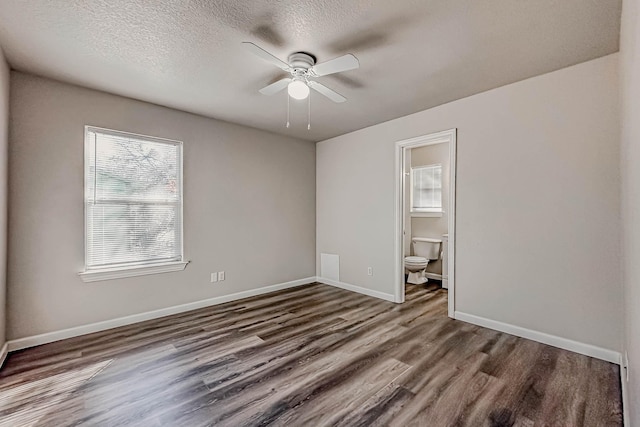 unfurnished bedroom featuring a textured ceiling, ensuite bathroom, ceiling fan, and dark wood-type flooring