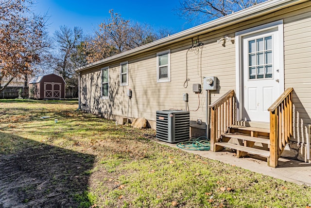 back of property featuring central AC unit, a storage shed, and a yard