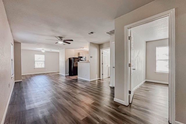 unfurnished living room featuring dark hardwood / wood-style floors, ceiling fan, and a textured ceiling