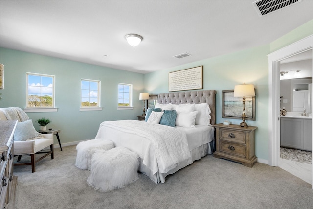 bedroom featuring light colored carpet, sink, and connected bathroom