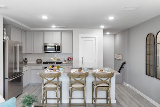 kitchen featuring a kitchen breakfast bar, a center island, light hardwood / wood-style floors, and appliances with stainless steel finishes