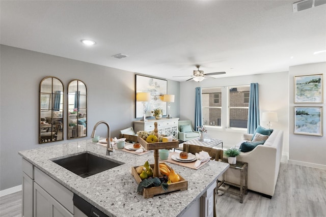 kitchen featuring white cabinets, sink, light hardwood / wood-style flooring, ceiling fan, and light stone countertops