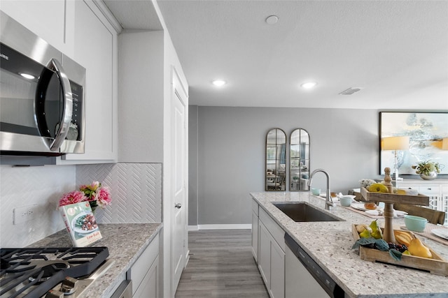 kitchen featuring decorative backsplash, sink, light stone countertops, and stainless steel appliances