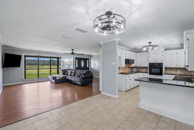 kitchen with sink, crown molding, backsplash, white cabinets, and oven