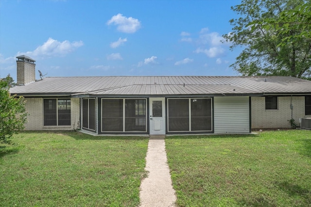 rear view of house with central AC, a lawn, and a sunroom