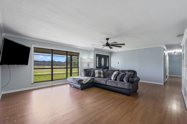 living room with ornamental molding, dark wood-type flooring, and ceiling fan