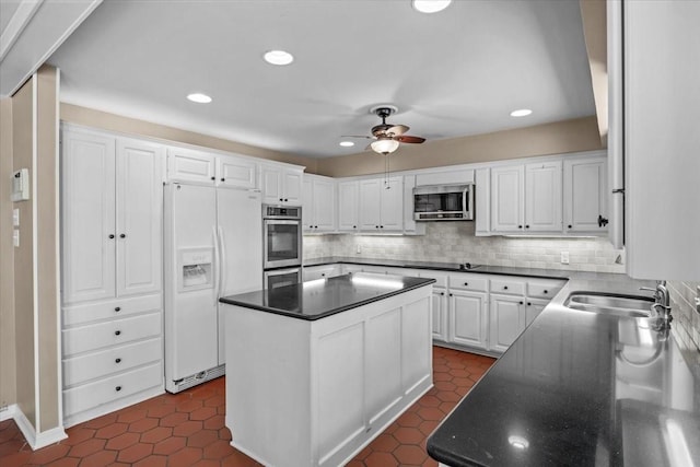 kitchen featuring white refrigerator with ice dispenser, sink, tasteful backsplash, a kitchen island, and white cabinetry