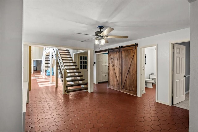 interior space with a barn door and ceiling fan