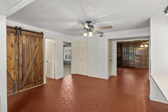 unfurnished room featuring a barn door and ceiling fan