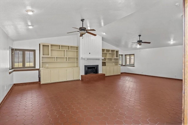 unfurnished living room featuring built in shelves, a large fireplace, vaulted ceiling, and plenty of natural light