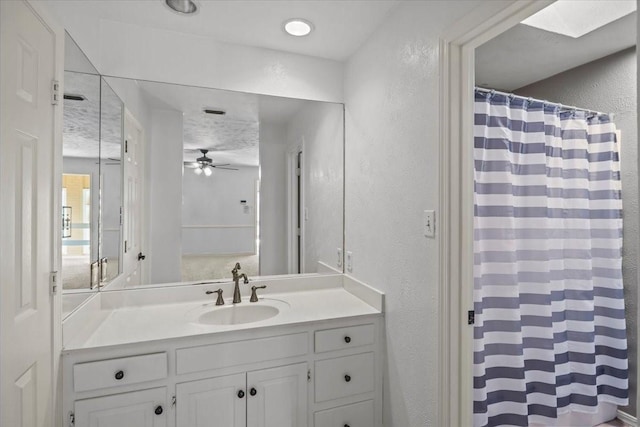 bathroom featuring vanity, ceiling fan, a textured ceiling, and a skylight