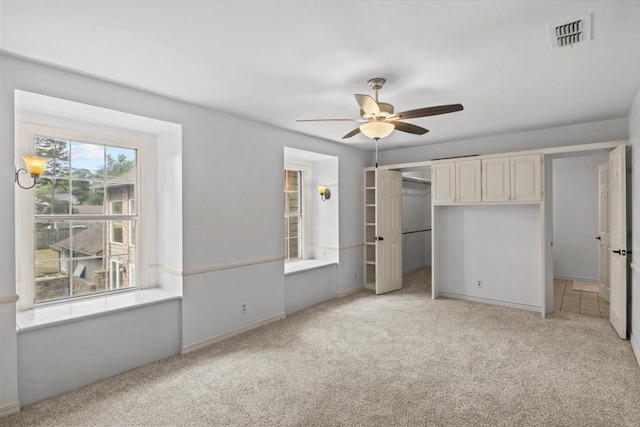 unfurnished bedroom featuring ceiling fan, a closet, and light colored carpet