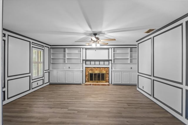 unfurnished living room with a fireplace, hardwood / wood-style flooring, built in features, and ornamental molding