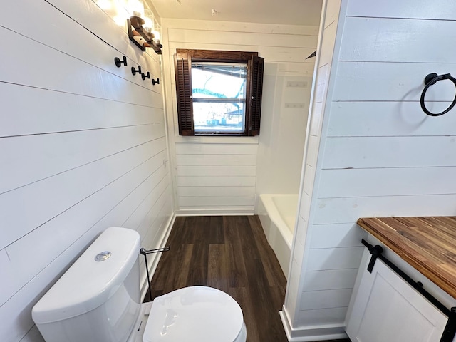 bathroom featuring wood-type flooring, vanity, toilet, and wood walls