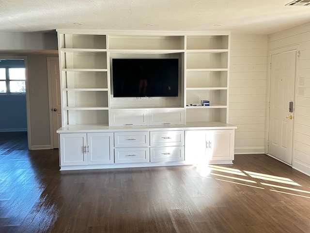 unfurnished living room featuring a textured ceiling, dark wood-type flooring, and wooden walls