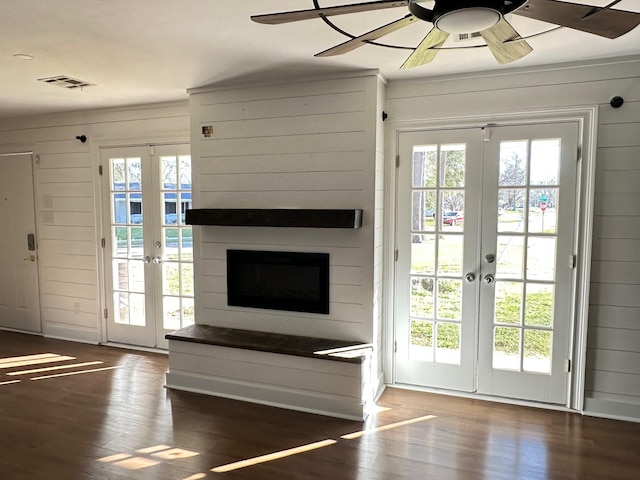 unfurnished living room with french doors, dark hardwood / wood-style flooring, a large fireplace, and a healthy amount of sunlight