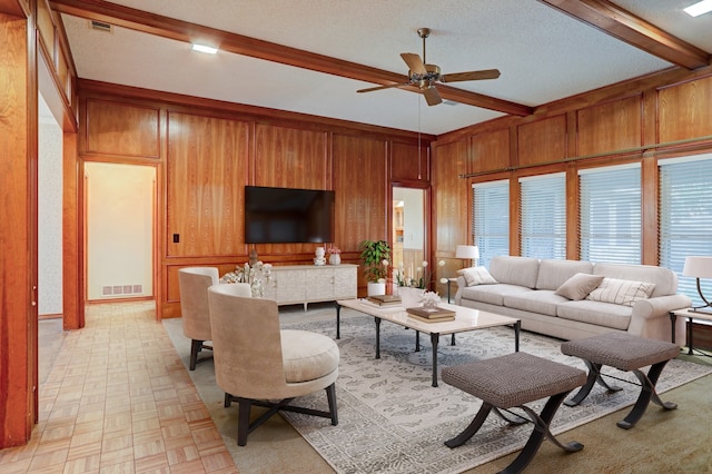 living room featuring wooden walls, beam ceiling, ceiling fan, light parquet flooring, and a textured ceiling