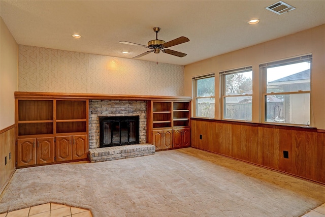 unfurnished living room featuring ceiling fan, light colored carpet, and a fireplace