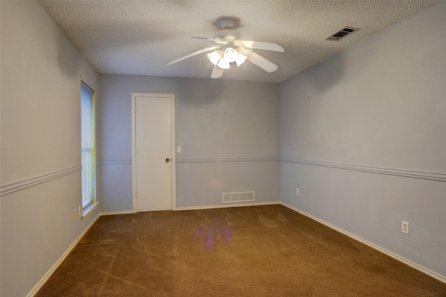 empty room featuring ceiling fan, dark carpet, and a textured ceiling