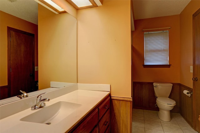 bathroom featuring vanity, tile patterned floors, wooden walls, and toilet