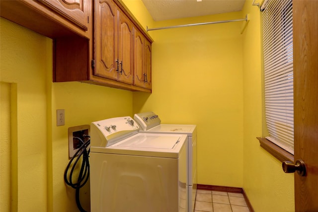 clothes washing area featuring cabinets, washer and dryer, and light tile patterned floors