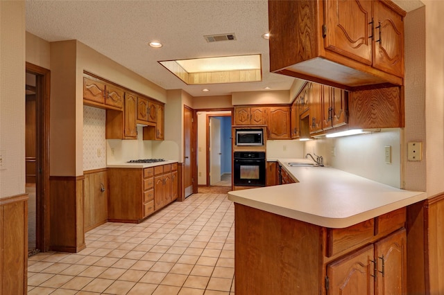 kitchen featuring light tile patterned flooring, appliances with stainless steel finishes, sink, kitchen peninsula, and a textured ceiling