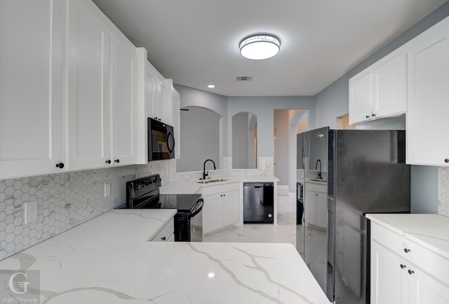 kitchen with sink, white cabinetry, backsplash, light stone countertops, and black appliances