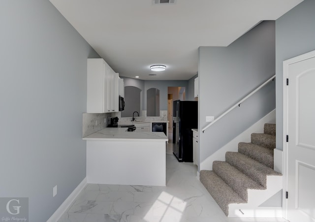 kitchen featuring sink, white cabinetry, backsplash, black appliances, and kitchen peninsula