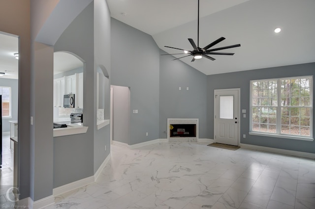 unfurnished living room featuring high vaulted ceiling and ceiling fan