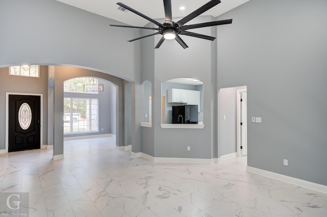 foyer with ceiling fan and a towering ceiling