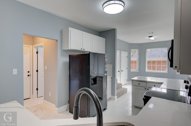 kitchen with white cabinets, stove, and black refrigerator with ice dispenser