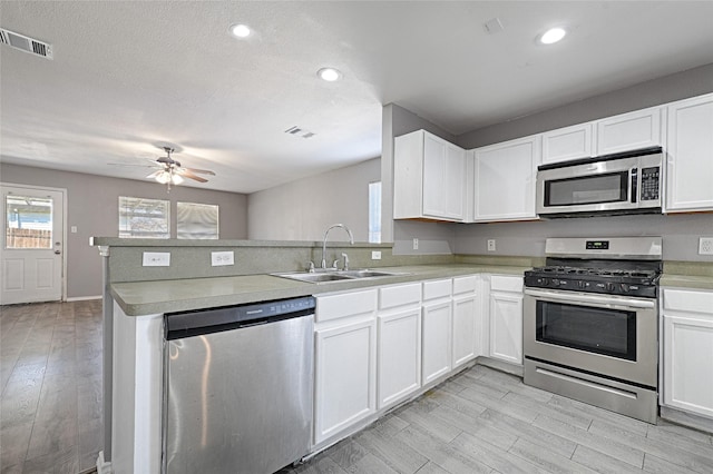 kitchen featuring sink, white cabinets, light hardwood / wood-style floors, kitchen peninsula, and stainless steel appliances