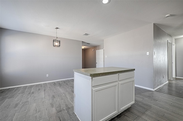 kitchen featuring white cabinetry, a center island, a textured ceiling, pendant lighting, and light hardwood / wood-style floors