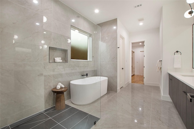 bathroom with a bathing tub, vanity, and tile walls